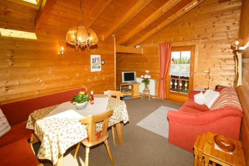 a living room with a red couch and a table at Ferienwohnung Heidi Steinbacher in Ruhpolding