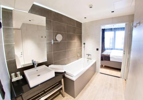 a bathroom with a sink and a tub and a bed at Original Sokos Hotel Alexandra Jyväskylä in Jyväskylä