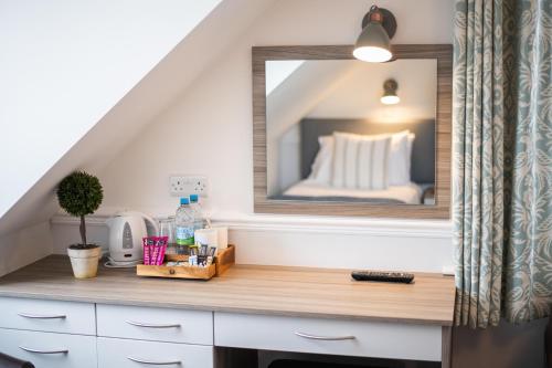 a room with a desk with a mirror and a bed at The Kingswood Hotel in Sidmouth