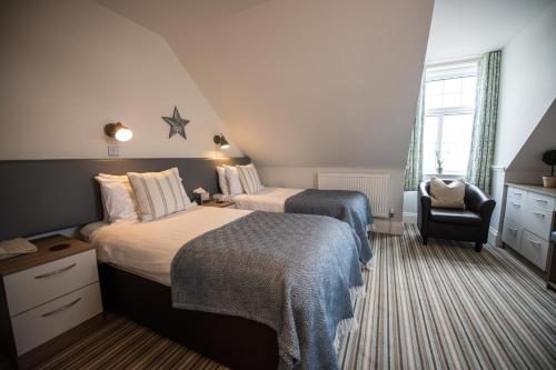a hotel room with two beds and a chair at The Kingswood Hotel in Sidmouth