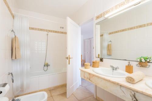 a white bathroom with a sink and a shower at Villa Ponent Galdana - Cala Galdana in Cala Galdana