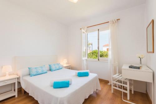 ein weißes Schlafzimmer mit einem Bett und einem Fenster in der Unterkunft Apartamento Savina-Arenal den Castell in Es Mercadal
