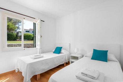 two beds in a white room with a window at Arenal Jardín 56-2 - Arenal den Castell in Arenal d'en Castell