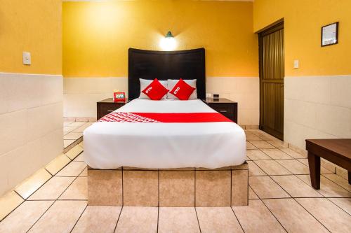 a bedroom with a large bed with red pillows at Hotel San Marcos in Los Mochis