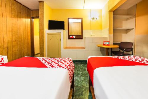 a room with two beds and a table and a tv at Hotel San Marcos in Los Mochis
