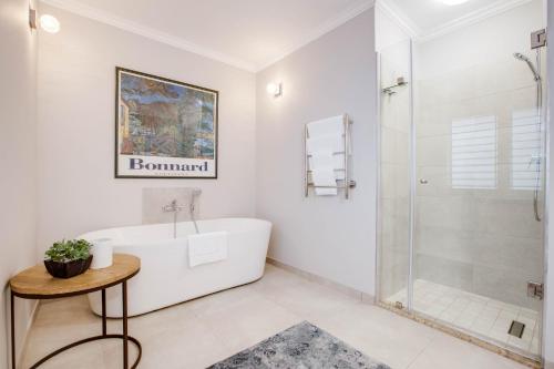 a white bathroom with a tub and a shower at Amberhall Guesthouse in Johannesburg