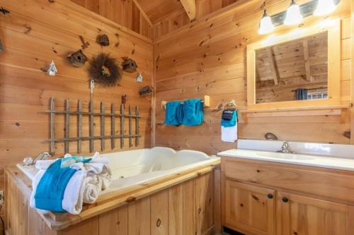 a bathroom with a tub and a sink in a cabin at Amazing Views! Hot Tub,Pool Table,Fireplace,Relax! in Gatlinburg