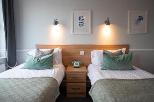 a bedroom with two beds and a night stand with a alarm clock at The Elizabeth in Sidmouth