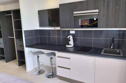 une cuisine avec un évier et un comptoir avec des tabourets dans l'établissement Naturiste Cap d'Agde Héliopolis D 11, au Cap d'Agde