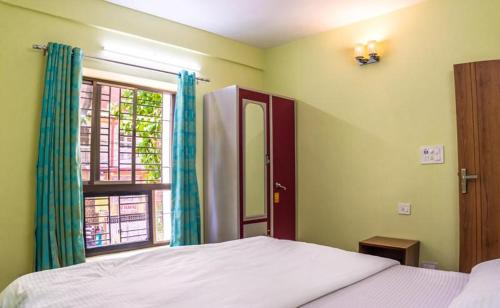 a bedroom with a bed and a window at Emerald By Olys Apartment in Kolkata