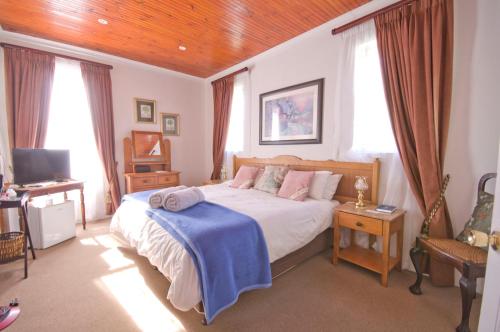 a bedroom with a bed with a blue blanket on it at Knysna Manor House in Knysna
