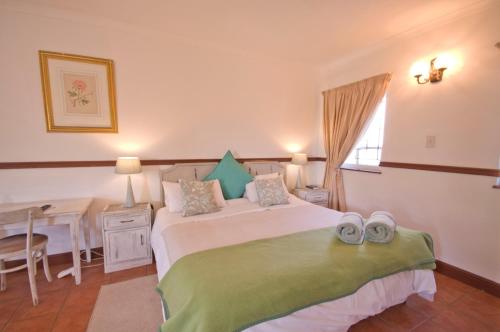 a bedroom with a bed and a table and a window at Knysna Manor House in Knysna
