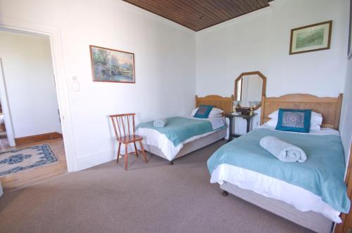 a bedroom with two beds and a mirror and a chair at Knysna Manor House in Knysna