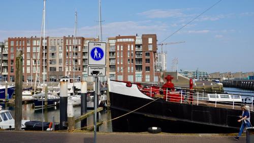 a boat is docked in a marina with buildings at Bizstay Harbour II Scheveningen Apartments in Scheveningen