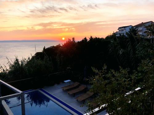 a sunset over the ocean with a swimming pool at LOFT-Beach-apartments RATKO in Novi Vinodolski