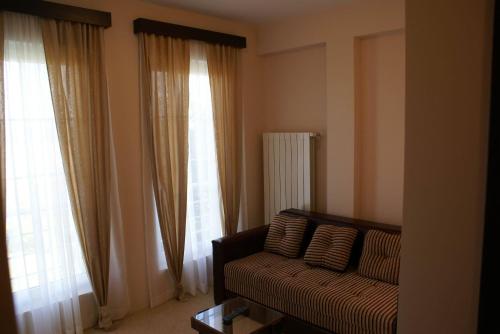 a living room with a couch and two large windows at B&B Vila Vidikovac in Arandjelovac