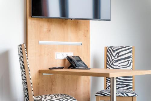 a desk with a phone and two chairs at Hotel No151 in Differdange