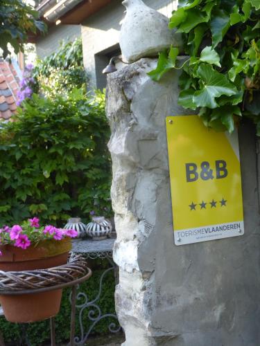 a sign on a stone wall with flowers and plants at De Epicurist in Hasselt
