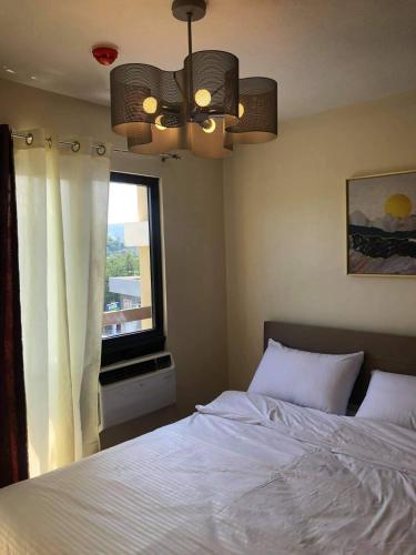 a bedroom with a white bed and a window at Lou Condo Rental in Cagayan de Oro