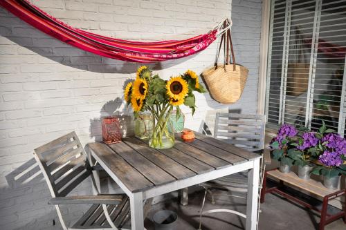 Boutique Studio Magielsen في أمستردام: طاولة خشبية مع إناء من زهور الشمس على الفناء