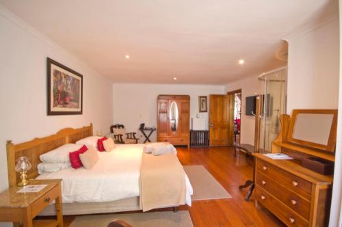 a bedroom with a bed and a dresser and a television at Knysna Manor House in Knysna