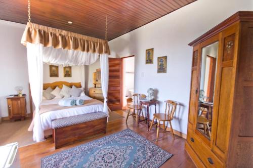 a bedroom with a bed and a table and chairs at Knysna Manor House in Knysna
