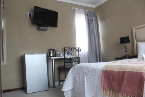 a hotel room with a bed and a television on the wall at The Anne Guest House in Maseru