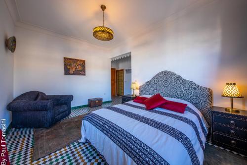 a bedroom with a large bed and a chair at Riad Fes Nass Zmane in Fès