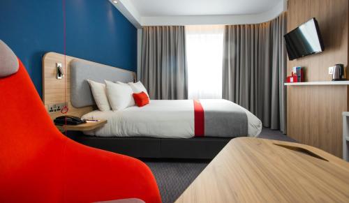 a hotel room with a bed and a red chair at Holiday Inn Express Burton on Trent, an IHG Hotel in Burton upon Trent