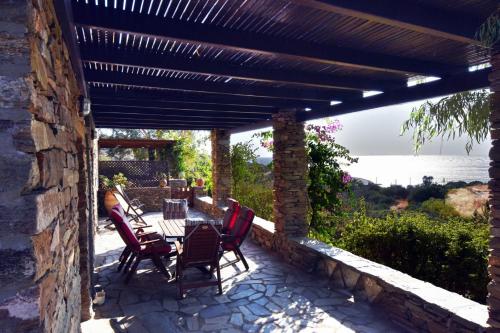 a patio with a table and chairs under a wooden pergola at family home with a fantastic sea view, 5 minutes from the beaches in Koundouros