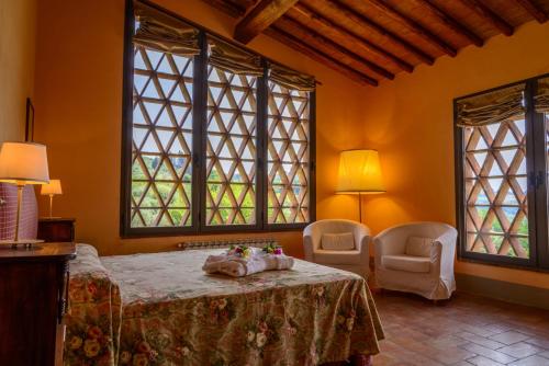a bedroom with a bed and two chairs and windows at Podere Vigliano in Tavarnelle in Val di Pesa