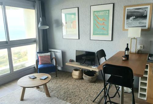 Una sala de estar con un escritorio, una mesa y sillas. en Victoria Surf Biarritz 102, en Biarritz
