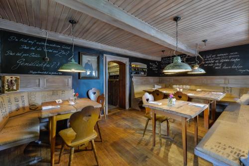 a restaurant with wooden tables and chairs and a chalkboard at RamsAu-das Gasthaus in Bad Heilbrunn