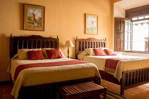 a bedroom with two beds and a window at Hotel Aurora in Antigua Guatemala