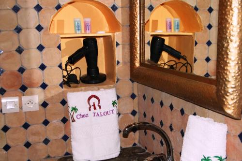 a bathroom sink with a mirror and a towel dispenser at Taloute Ecolodge in Skoura