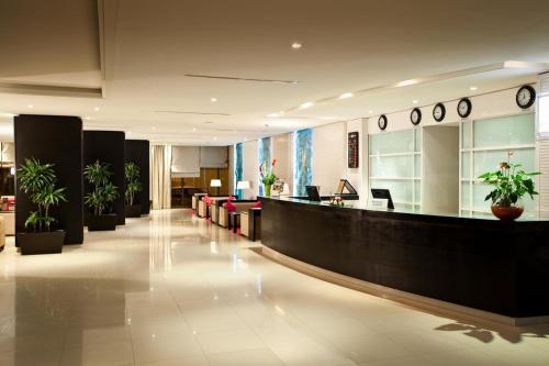 a lobby with a waiting area with plants and clocks at Concorde Sfax Centre in Sfax