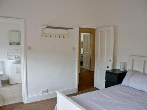 a white bedroom with a bed and a sink at Corner House Apartment in Worthing