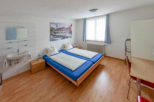 ein Schlafzimmer mit einem Bett und einem Waschbecken darin in der Unterkunft Hirschen Backpacker-Hotel & Pub in Schwyz