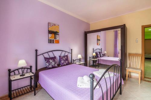 a bedroom with a purple bed and a mirror at T2 Anastácio com vista Jardim in Olhos de Água