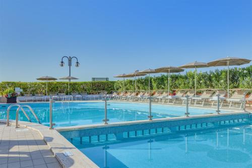a swimming pool with chairs and umbrellas at Hotel Delle Mimose in Lido di Jesolo