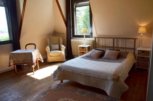 a bedroom with a bed and a chair and window at le château des arènes in Gières