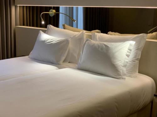 a white bed with white pillows on top of it at Hotel Cristal Setúbal in Setúbal