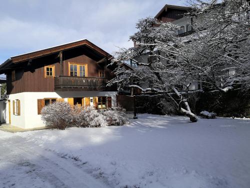 une maison avec une cour recouverte de neige devant elle dans l'établissement Ferienhaus Erika, à Garmisch-Partenkirchen