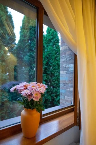 an orange vase with flowers sitting on a window sill at Hotel Bohemia in Bacău