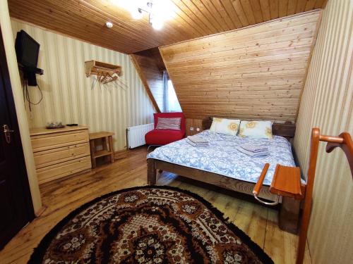 a small bedroom with a bed and a red chair at Вотавілю Драгобрат in Dragobrat