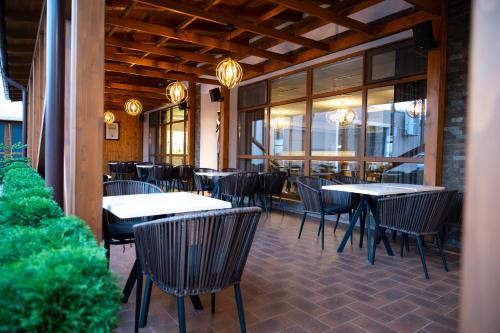 a restaurant with tables and chairs and windows at Hotel Bohemia in Bacău