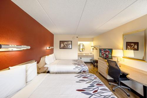 a hotel room with two beds and a desk at Red Roof Inn Fairmont in Fairmont