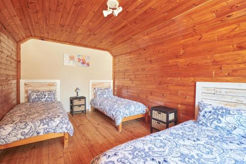 two beds in a room with wooden walls at Citrus Creek Chalets in Citrusdal