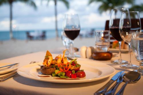 a plate of food on a table with wine glasses at Galley Bay Resort & Spa in Saint Johnʼs