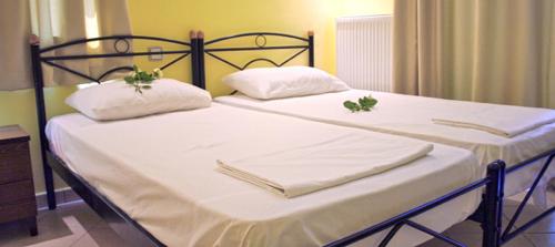 two beds in a bedroom with white sheets and pillows at Kalloni Beach Villas in Skala Kallonis